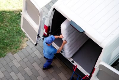 Hauling worker loading a heavy mattress into the back of a moving van for eco friendly disposal in Lighthouse Point Florida